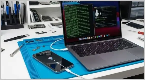 iPhone connected to a MacBook running Checkra1n terminal software for iCloud bypass.